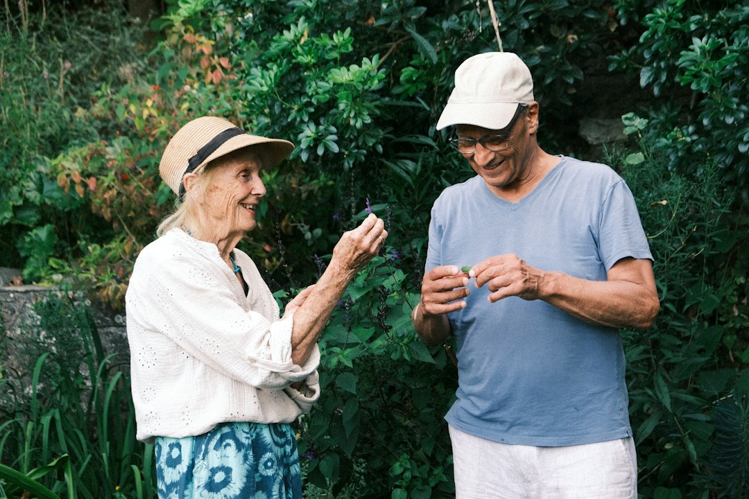 An older woman and man examining small leaves in a lush green garden