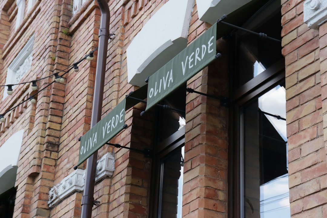 Green fabric signs reading OLIVA VERDE on a red brick building facade