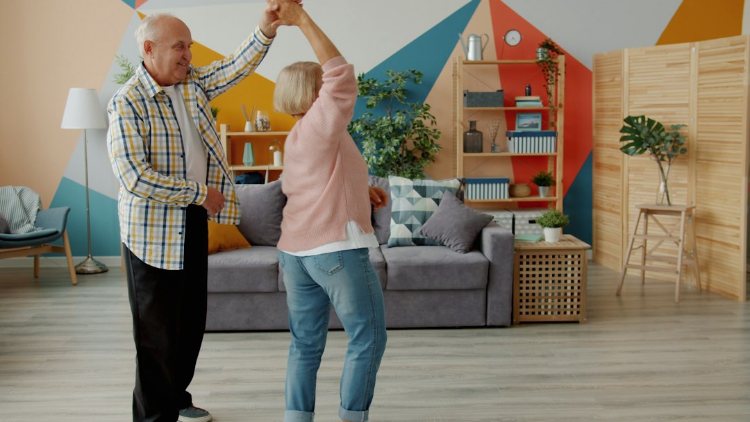 Elderly couple dancing joyfully in a living room